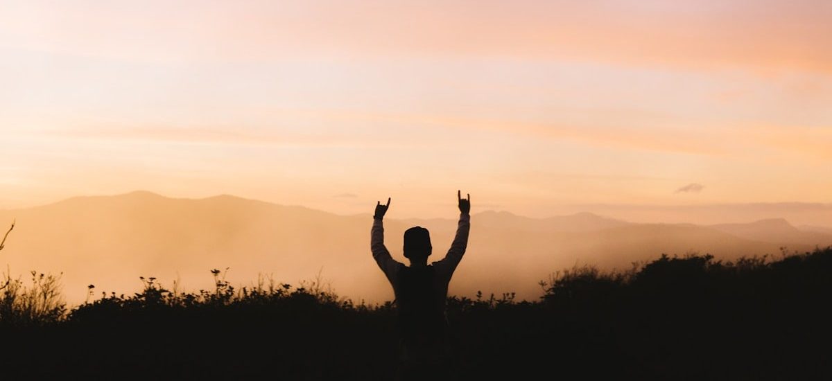 silhouette photography of person racing hands in front of mountain