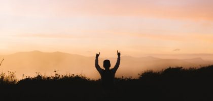 silhouette photography of person racing hands in front of mountain
