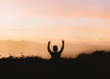 silhouette photography of person racing hands in front of mountain